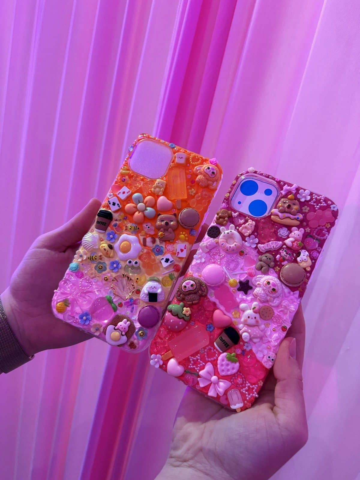 Two finished decoden phone cases held up side by side