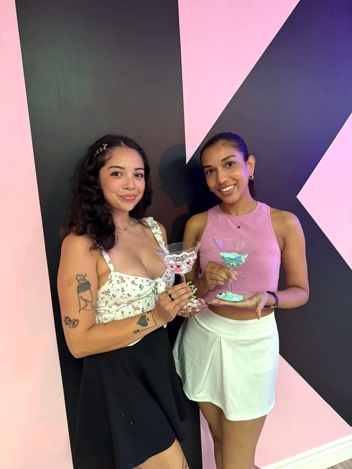 Two friends with their charm martini glasses in front of the K wall